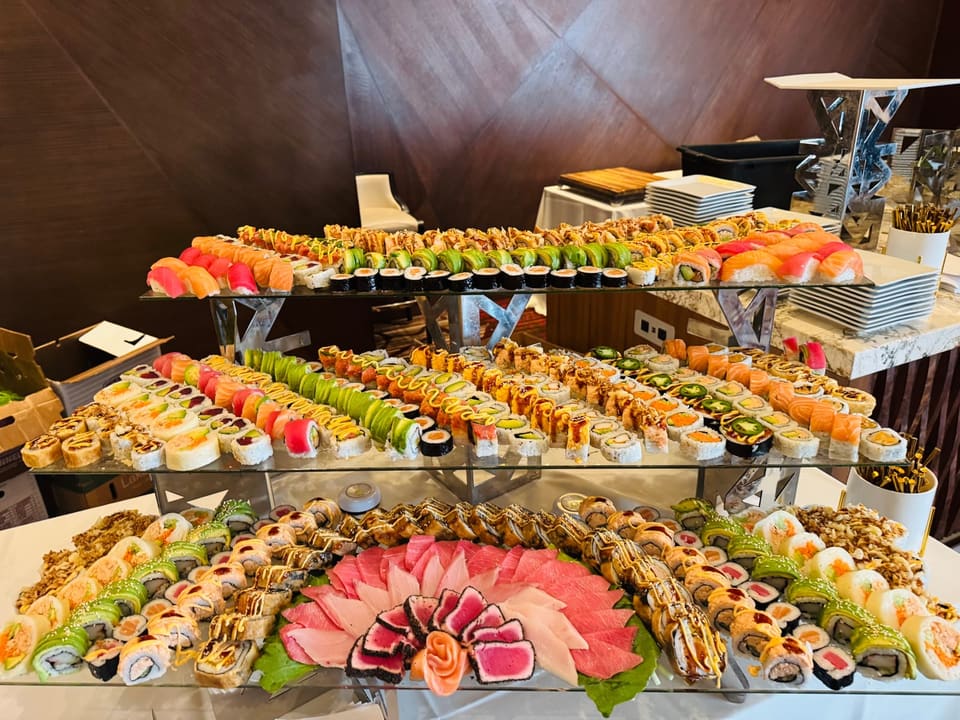 A three-tier glass stand built up with rows of rolls on each level and a flower of sashimi on the lowest, assembled at the venue.